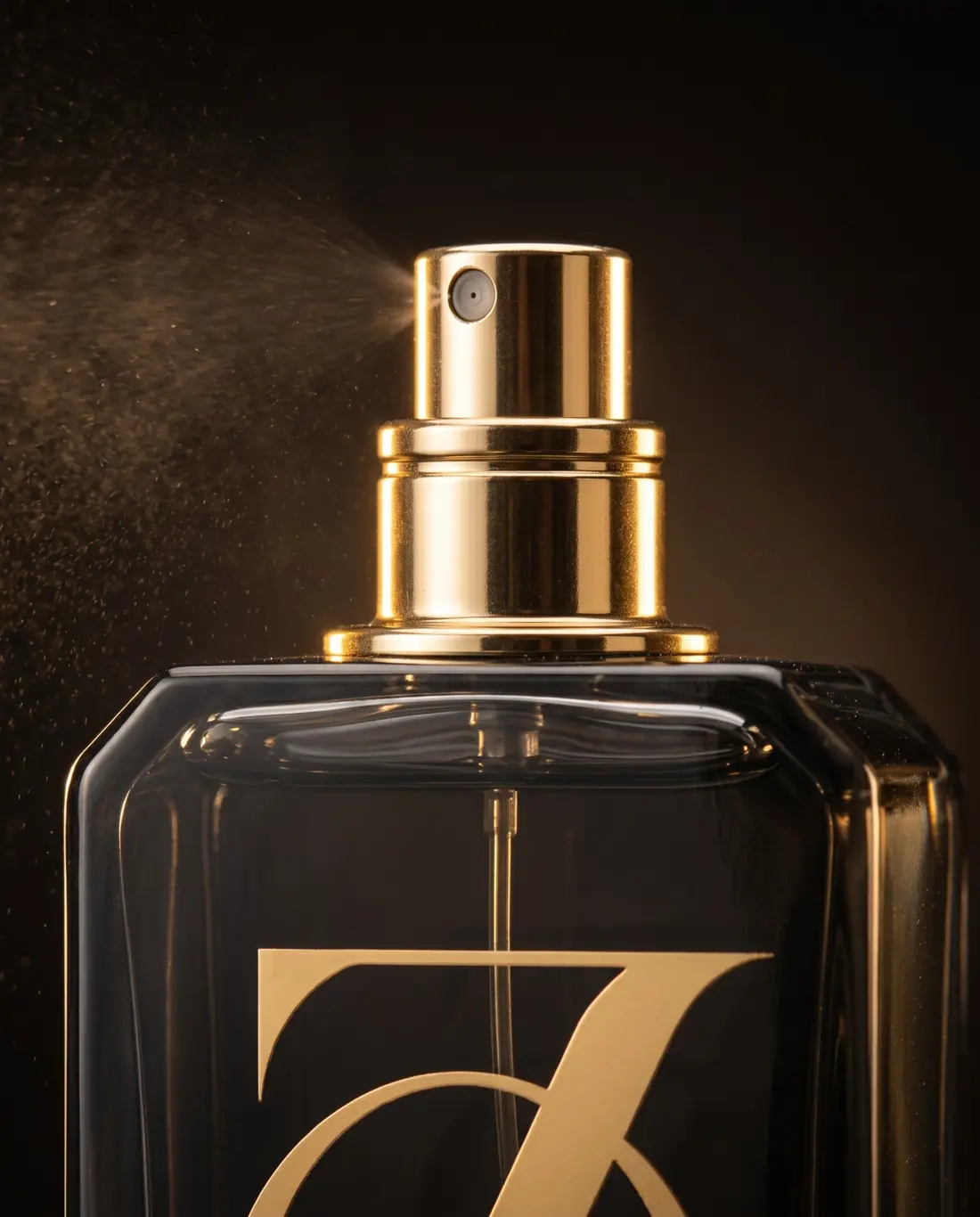 Close view of the gold atomizer spraying a fine perfume mist
